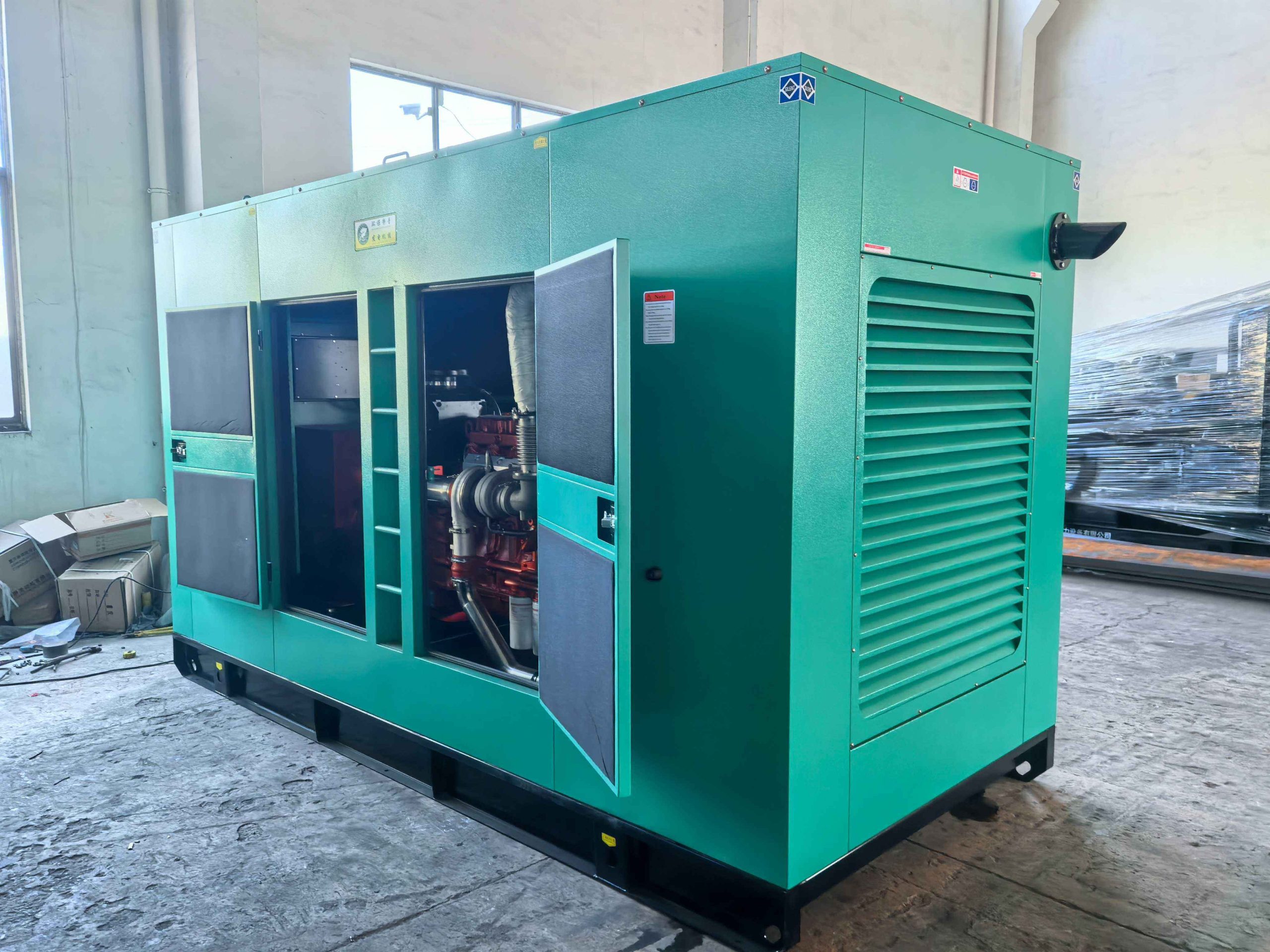 Sound-attenuated canopy diesel generator set with side access doors open in a workshop